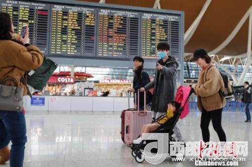 旅客帶著孩子前往辦票柜臺辦理登機手續(xù)?！∫罅⑶?攝